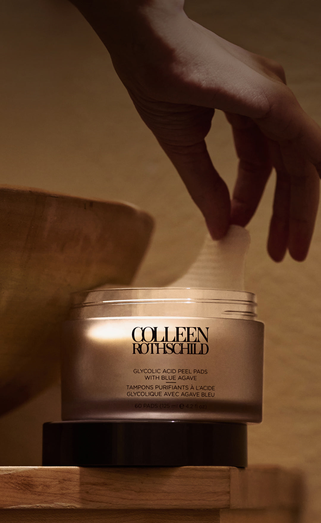 Hand holding Colleen Rothschild Beauty Glycolic Acid Peel Pads next to sink.