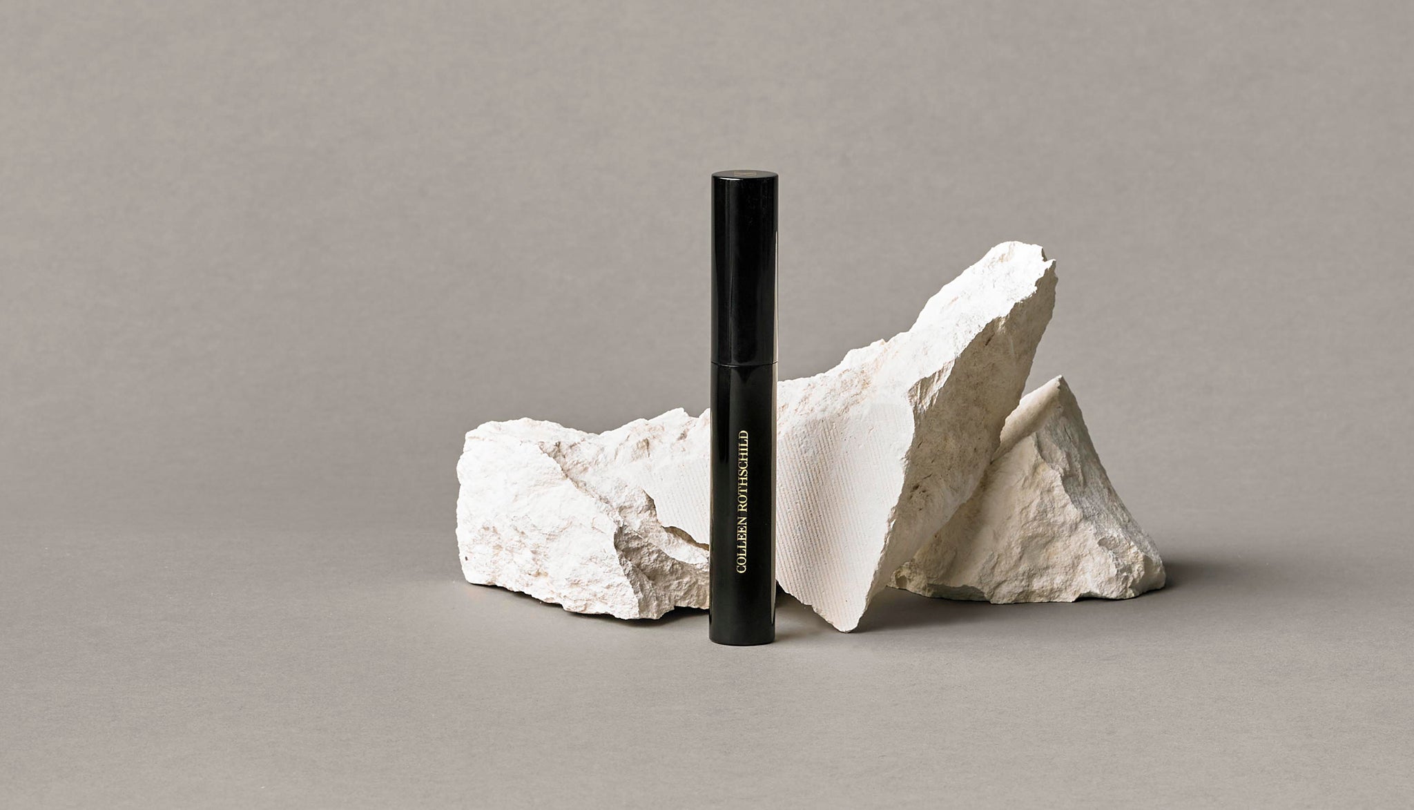 Colleen Rothschild Beauty black Panoramic Mascara tube in front of rock and neutral background.