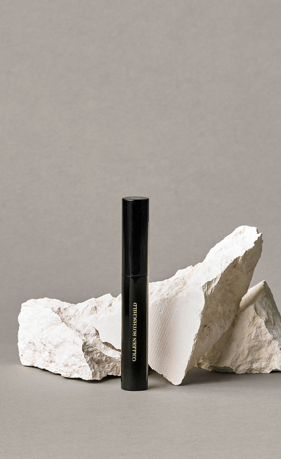 Colleen Rothschild Beauty black Panoramic Mascara tube in front of rock and neutral background.