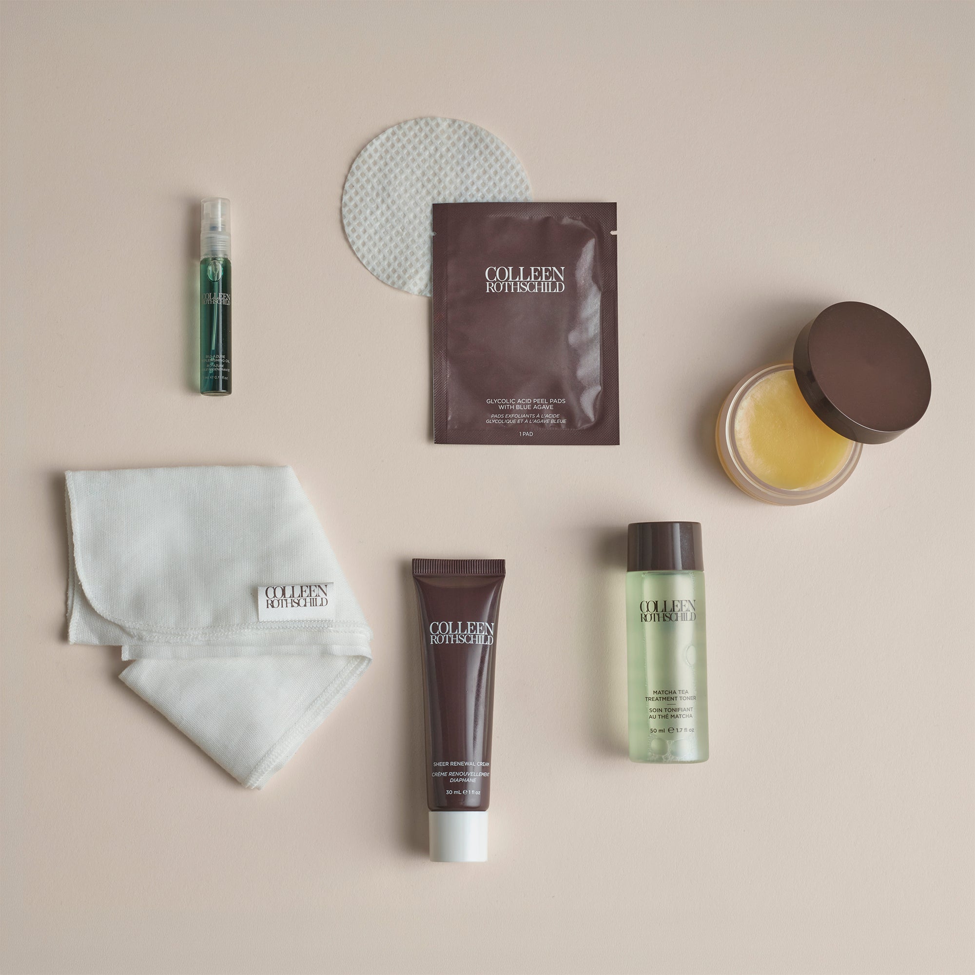 A flat-lay arrangement of six Collagen Boosted skincare products on a warm beige background, including a white cotton pad, a small green spray bottle, a brown sachet, a folded white cloth, a dark brown tube, a clear bottle with pale green liquid, and a jar of yellow balm.
